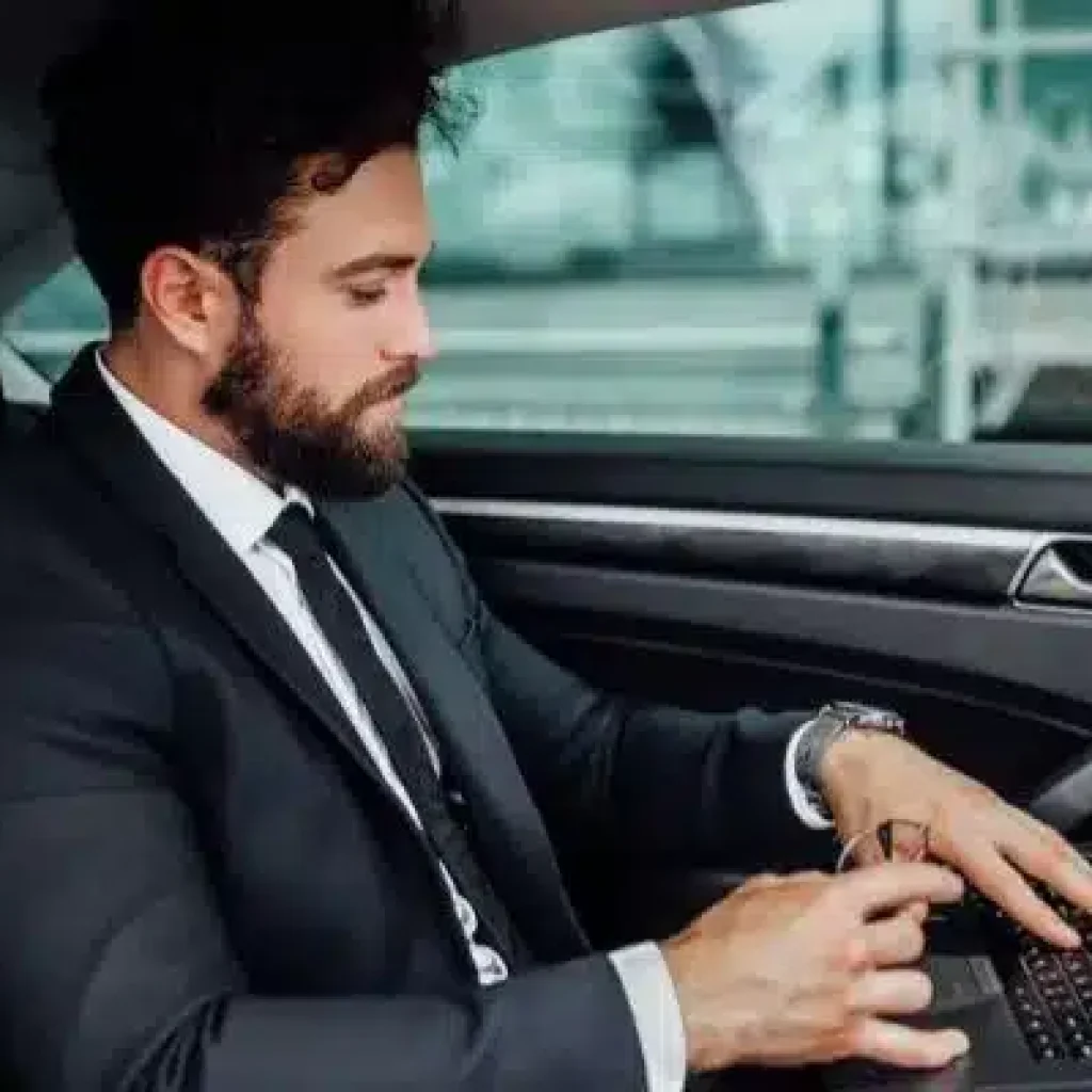 Executive working on laptop inside premium chauffeur-driven car