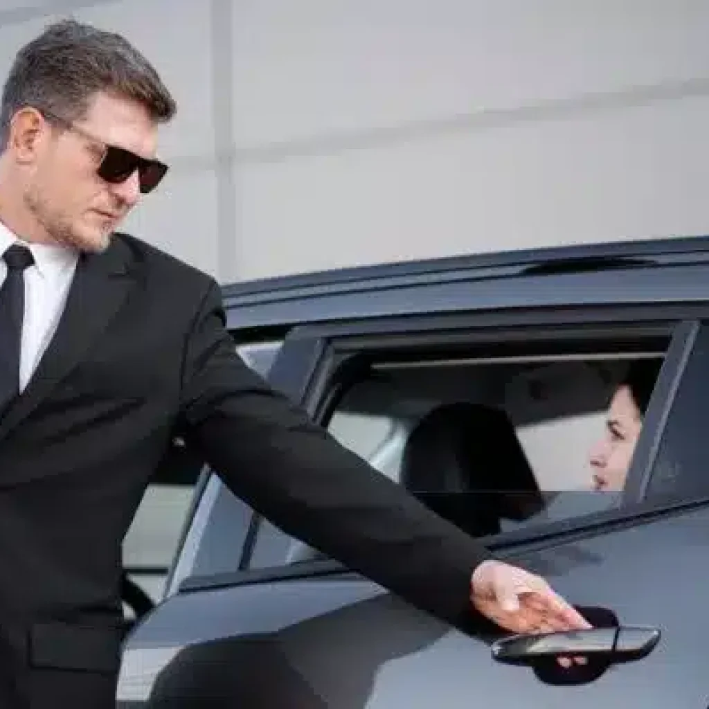 Luxury chauffeur service assisting passenger with car door outside hotel