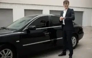 Professional chauffeur standing beside luxury black sedan for VIP Connection executive transportation service in New York City